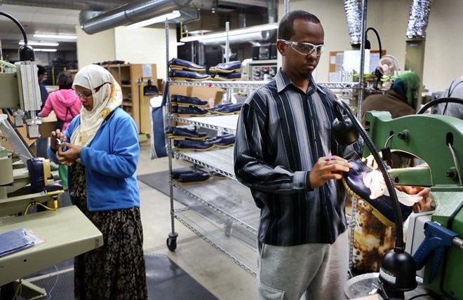 In this Tuesday, Jan. 26, 2016 photo, Abdi Said, right, trims the rubber bottoms of Bean Boots at an L.L. Bean factory in Lewiston, Maine. Said, a refugee, was originally put in San Jose, California, before he moved cross-country to Lewiston. “We are working hard and we're going to school and everything - like regular American people. They see that we are not different,” he said. (AP Photo/Robert F. Bukaty)