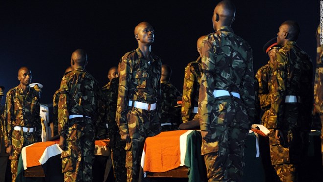 Kenyan soldiers stand over caskets bearing the remains of four slain comrades.