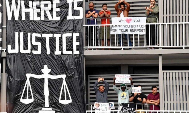 A group of detained asylum seekers are seen during a protest outside the Kangaroo Point Central Hotel in Brisbane in August. A Somalian man has been transferred from the hotel after an act of self harm. He has been unable to see his wife and child since Covid-19 restrictions were imposed in March. Photograph: Darren England/AAP