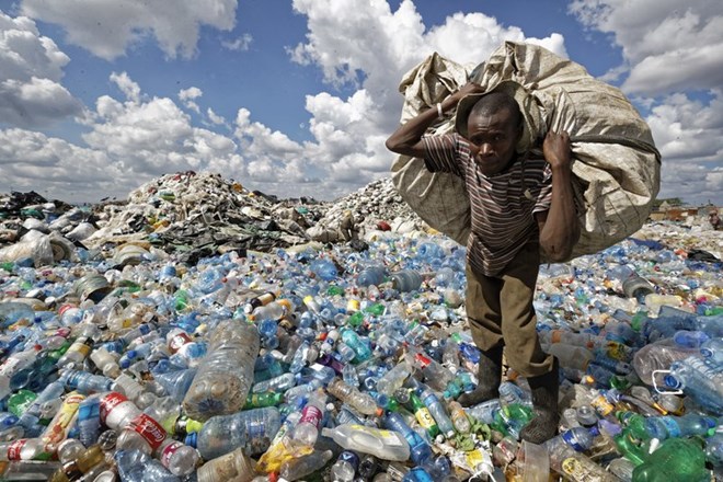 In this Wednesday, Dec. 5, 2018 file photo, a man walks on a mountain of plastic bottles as he carries a sack of them to be sold for recycling after weighing them at the dump in the Dandora slum of Nairobi, Kenya. The oil industry in 2020 has asked the United States to pressure Kenya to change its world-leading stance against the plastic waste that litters Africa, according to environmentalists who fear the continent will be used as a dumping ground. (AP Photo/Ben Curtis, File)