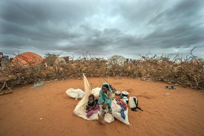 A Somali woman and child wait to be given a spot to settle at a camp for displaced people on the outskirts of Dollow, Somalia on Tuesday, Sept. 20, 2022. Somalia has long known droughts, but the climate shocks are now coming more frequently, leaving less room to recover and prepare for the next. (AP Photo/Jerome Delay)