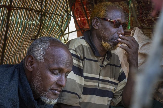 Mohamed Kheir Issack, 80, right, and Issack Farow Hassan, 75, sit in Issack's shelter at a camp for displaced people on the outskirts of Dollow, Somalia on Tuesday, Sept. 20, 2022. The two blind men are friends and as close as brothers, gripping each other's hands in their mutual darkness as tightly as they hold their canes. Near the end of their lives, the most alarming drought in more than half a century in Somalia has stripped them of their animals and homes. (AP Photo/Jerome Delay)