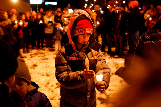 Elias David-Schill, 11, keeps the wind from blowing out his candle at Tuesday nights rally in support of Juba Restaurant Jesse Trelstad/ Grand Forks Herald