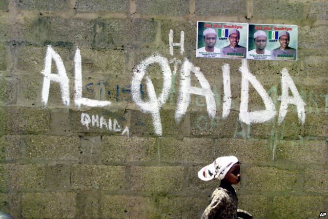 A girl walks past a wall with graffiti about the al-Qaida network in the northern city of Kano, Nigeria.