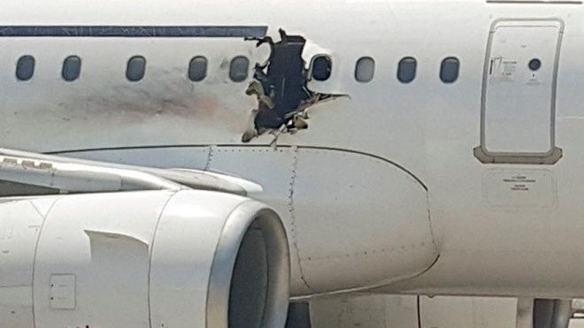 A hole is photographed in a plane operated by Daallo Airlines as it sits on the runway of the airport in Mogadishu, Somalia. Abdullahi Abdisalam Borleh boarded the plane on Feb. 2 with a bomb which exploded at 11,000 feet. (AP Photo, File