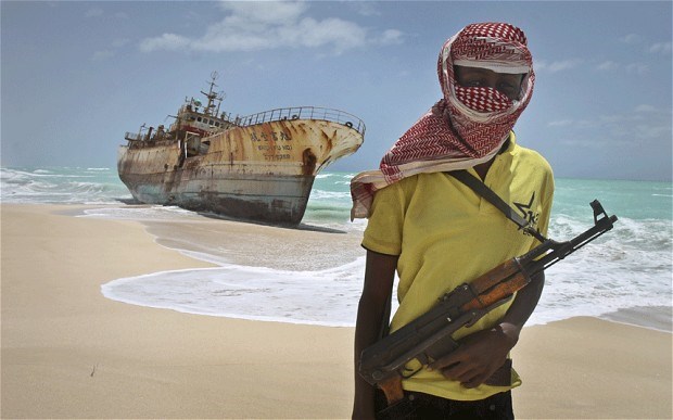 Scourge of the seas: a masked Somali pirate stands near a hijacked Taiwanese fishing vessel n the once-bustling pirate den of Hobyo, Somalia.  Photo: AP Photo/Farah Abdi Warsameh