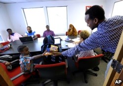 FILE - Somali immigrant leader Jamal Dar, right, who arrived in the U.S. two decades ago, hands out snacks to a boy at a community engagement and civic language class for former Somali residents at AYCO offices in East Portland, Ore., July 21, 2015.