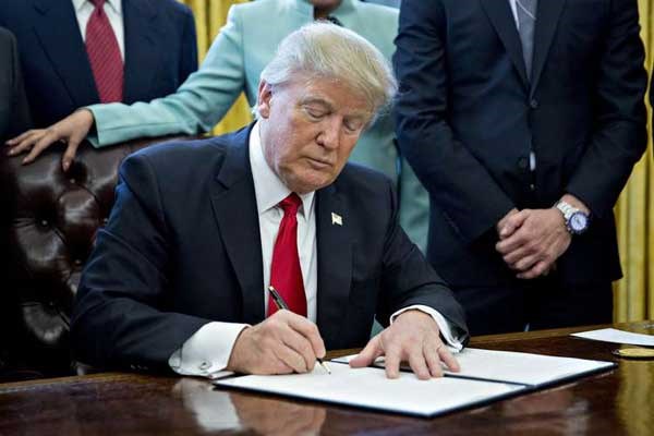 US President Donald Trump signs an executive order in the Oval Office of the White House in Washington, DC, USA, 30 January 2017. PHOTO | ANDREW HARRER | EPA