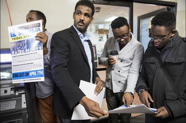 Khalid Mohamed, from right, hands out flyers to Mohamud Isse, Muhiadin Mohamud, and Faysal Ali to raise awareness for Dine Out for Somalia at the Village Market mall in Minneapolis.