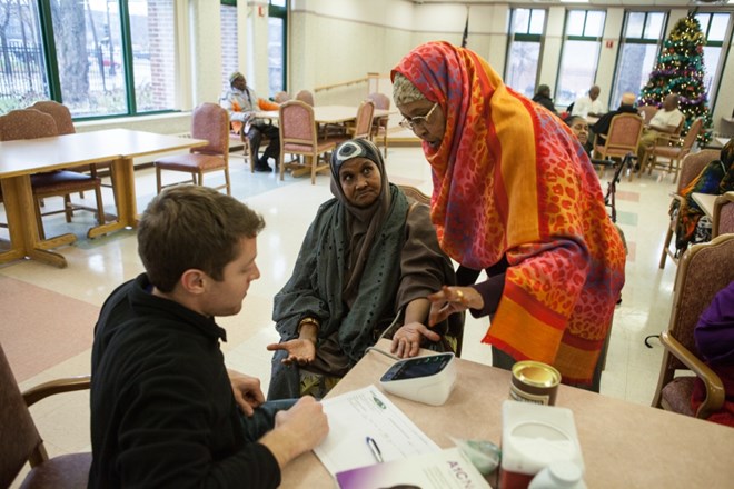 Sahra Ali, right, checks the blood pressure of an elderly Somali woman at a high-rise in South Minneapolis on December 8, 2015. It was part of a health outreach program that ended in early 2017.