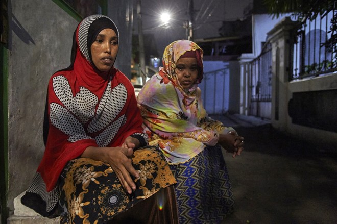 Stahil and Safiya sit in a Jakarta street at night. There are 13,800 asylum seekers and refugees in Indonesia. Two-thirds are dependent on aid or live in government-run immigration detention centres, according to the UNHCR.’