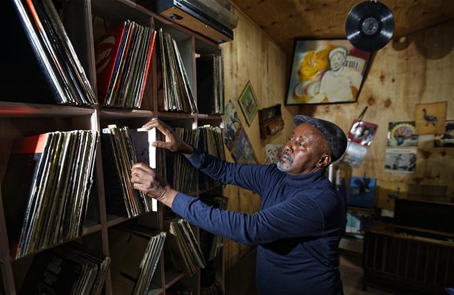 In this photo taken Thursday, March 1, 2018, James "Jimmy" Rugami looks through records inside his vinyl records stall in Kenyatta Market in Nairobi, Kenya.   (AP Photo/Ben Curtis)
