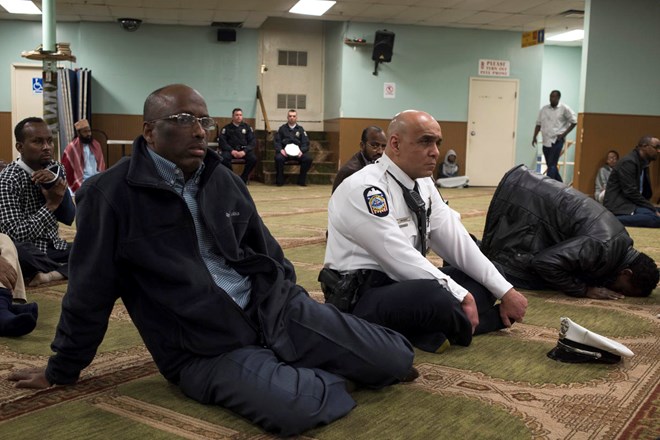 In this Feb. 23, 2018, photo, New American Diversity and Inclusion Officer Khaled Bhagat, with the Columbus Police Department, sits on the floor with other members at the Masjid Ibnu Taymiyah Islamic Center during Friday prayer in Columbus, Ohio. Bhagat has been tapped in Ohio’s capital to bridge gaps between police and the city’s growing immigrant population. (AP Photo/Ty Wright)